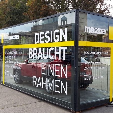 Ein Promotioncontainer mit Glaswänden und einem Auto im inneren