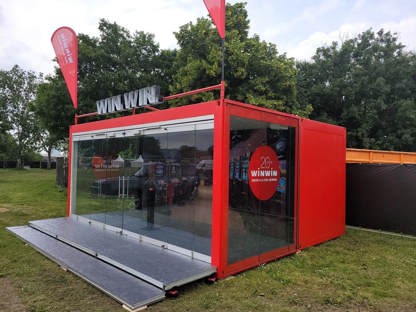 Ein roter Roadshow Container auf einer grünen Wiese